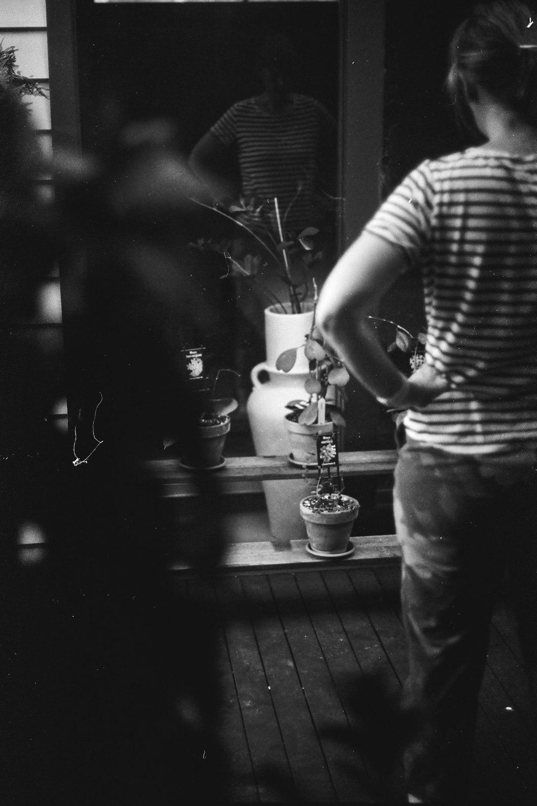 man in stripe shirt and black pants standing in front of window