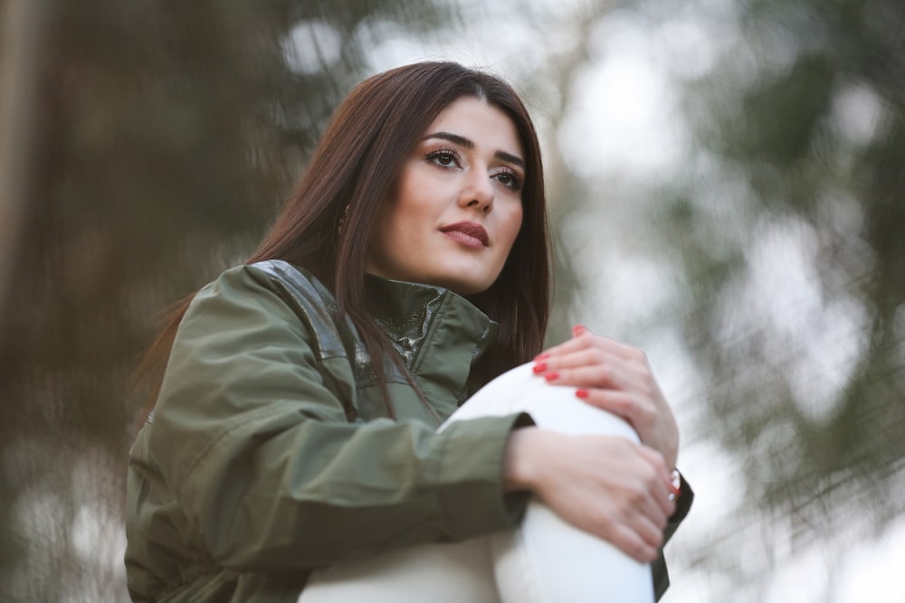 woman in green jacket holding white round ball