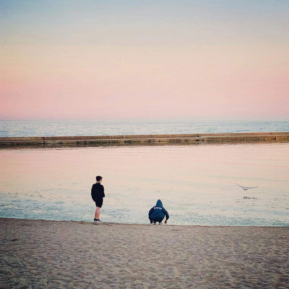 2 people walking on beach during daytime