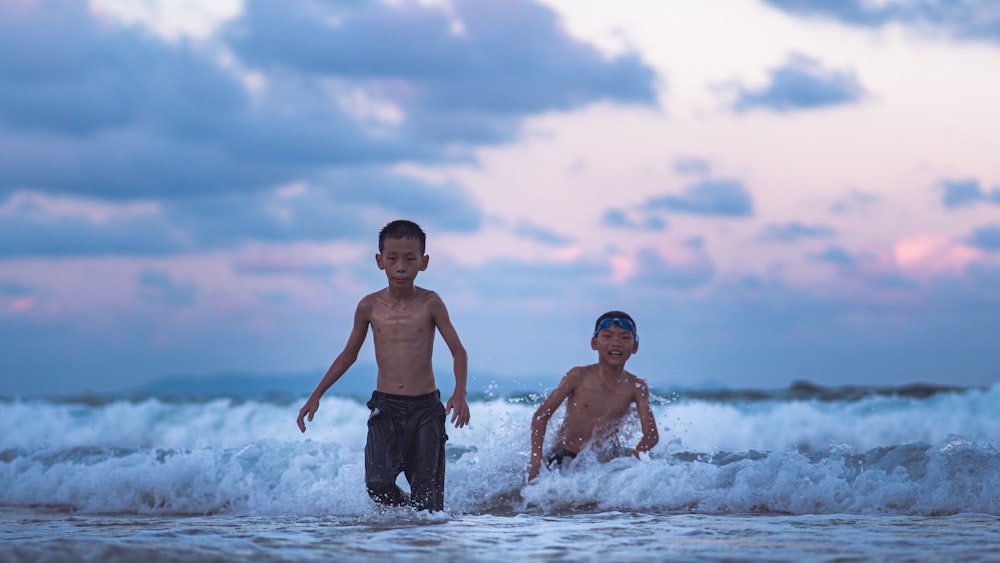 2 men in black shorts standing on beach during daytime