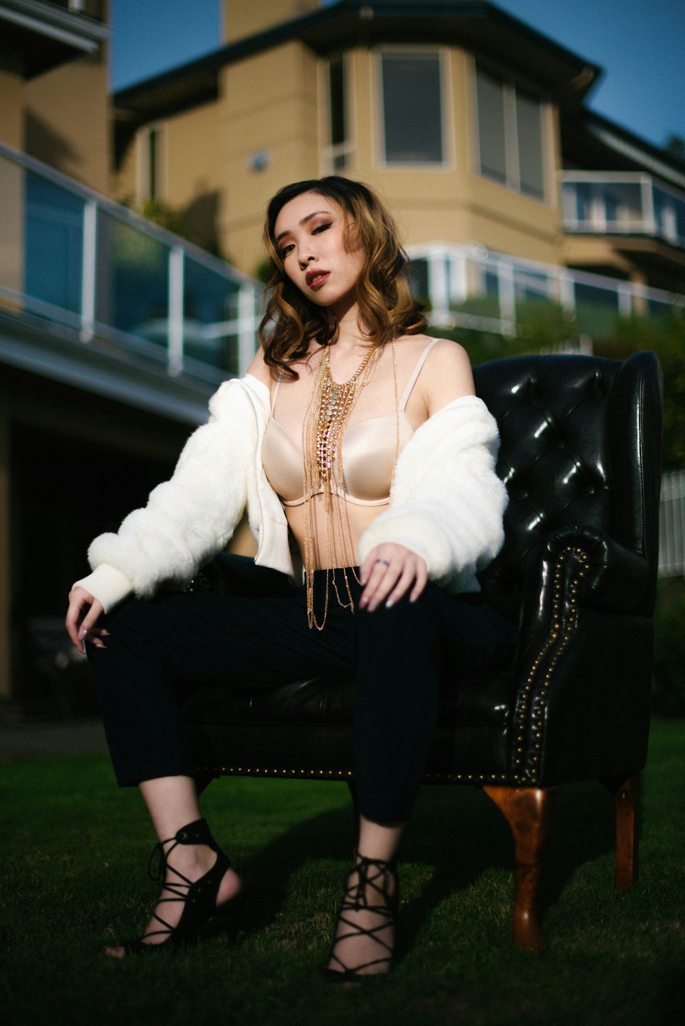 woman in white fur coat sitting on black leather sofa chair