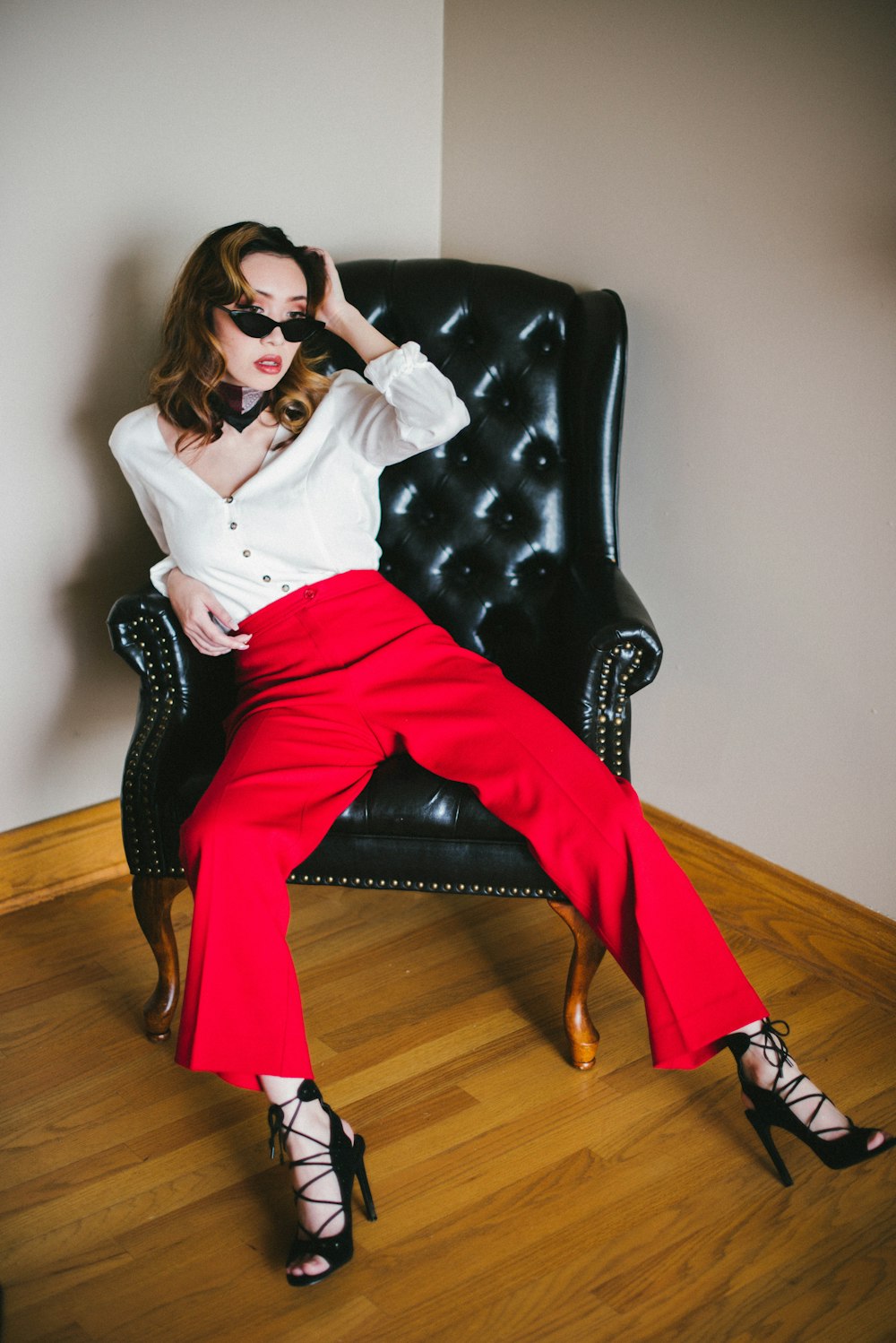 woman in white long sleeve shirt and red pants sitting on black leather sofa chair