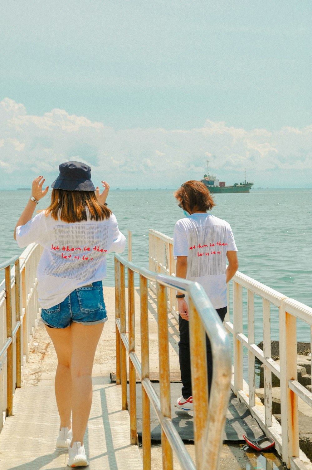 woman in white shirt and blue denim shorts standing on brown wooden dock during daytime