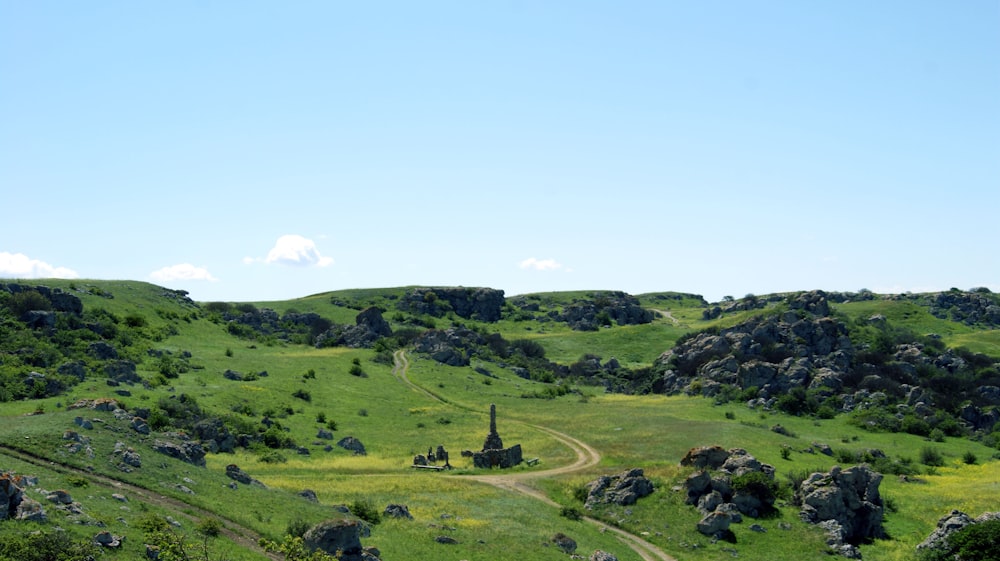 green grass field on hill under blue sky during daytime