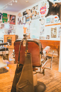 A cozy barber chair beside a vintage razor and scissors on a wooden counter at Schnittkunst.