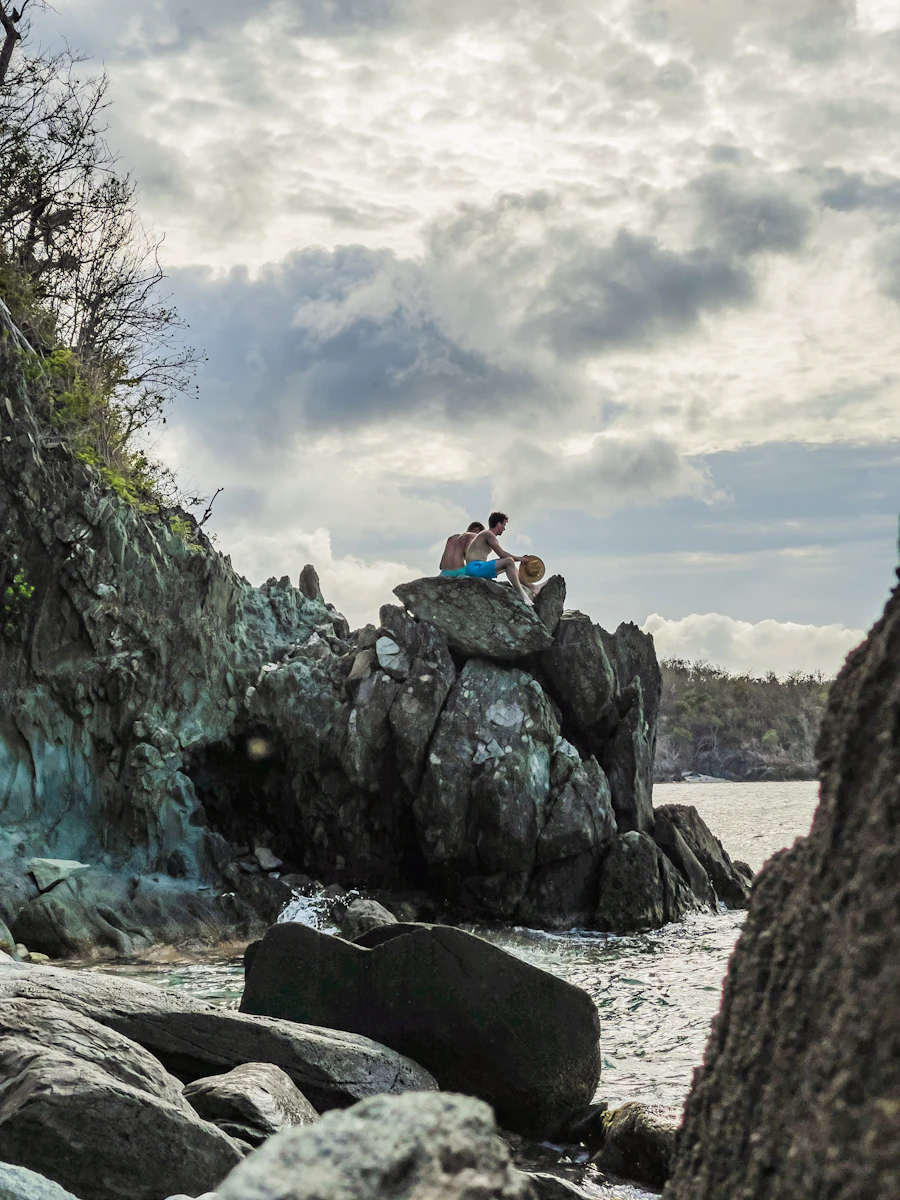 Person sitting on a rock formation overlooking the coast