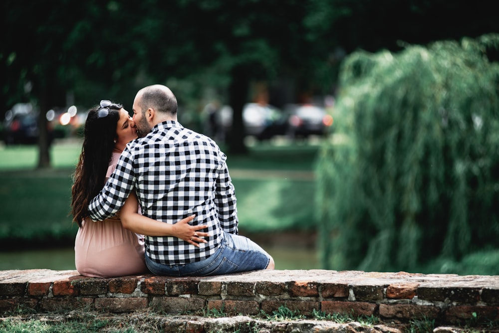 man in blue and white checkered dress shirt sitting on brown concrete bench during daytime