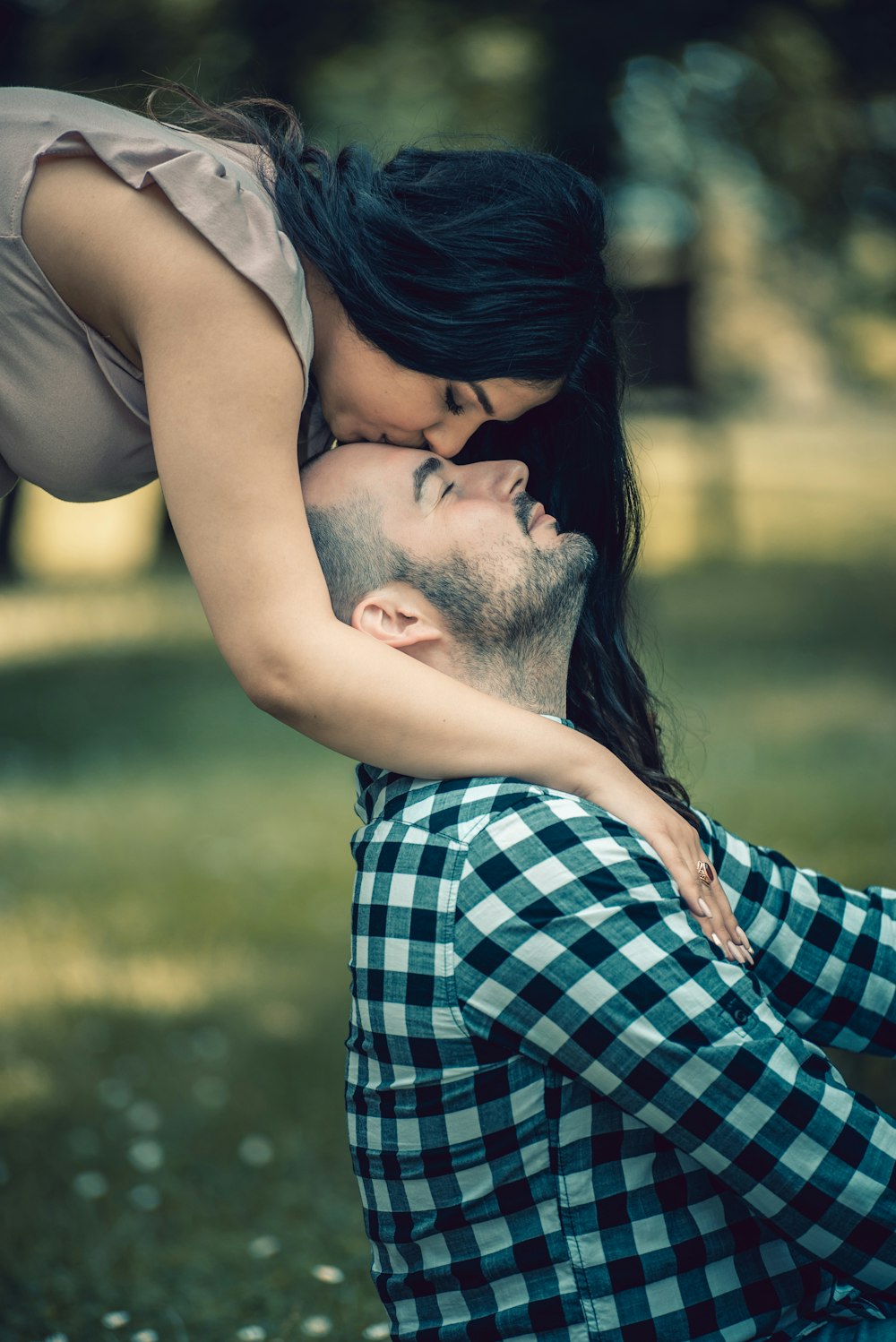 man in blue and white plaid dress shirt kissing woman in white tank top