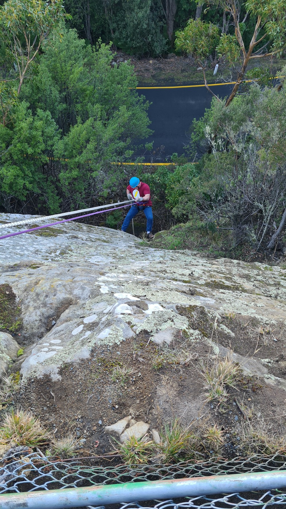 man in red and blue jacket and black pants walking on rocky mountain during daytime