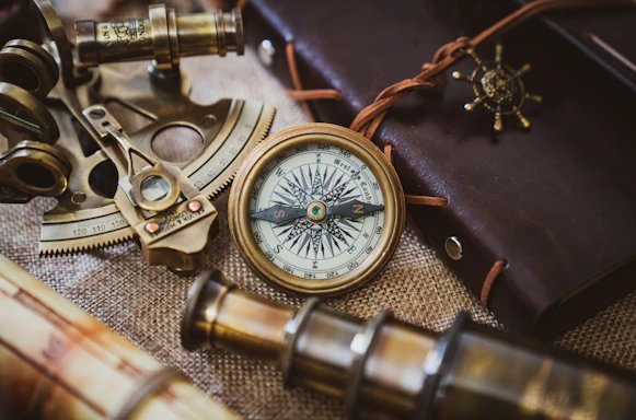 A vintage nautical map spread open on a wooden table with a compass and a sextant beside it.