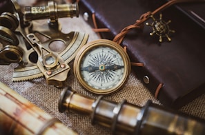 An antique brass astrolabe resting on a worn wooden desk scattered with parchment.
