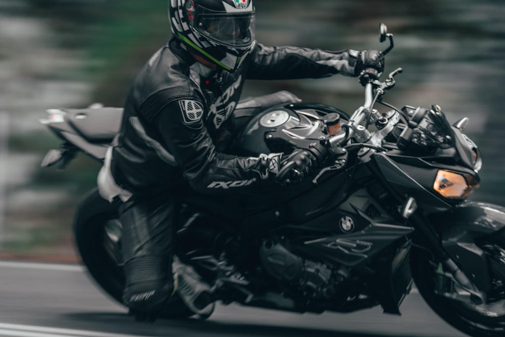 man in black motorcycle suit riding on black and white sports bike