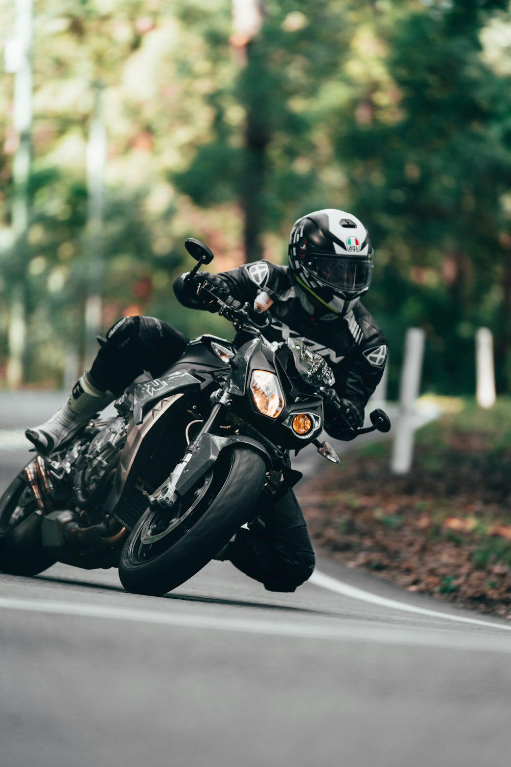 昼間、道路でオートバイに乗る黒いオートバイのヘルメットをかぶった男