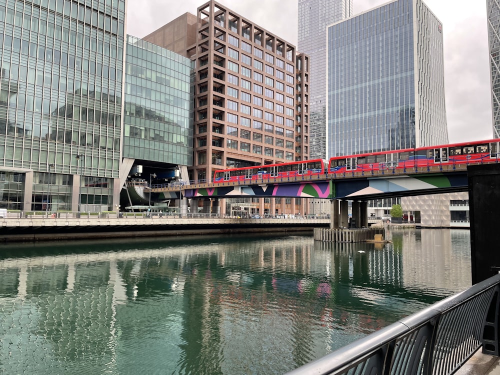 red bridge over river near high rise buildings during daytime