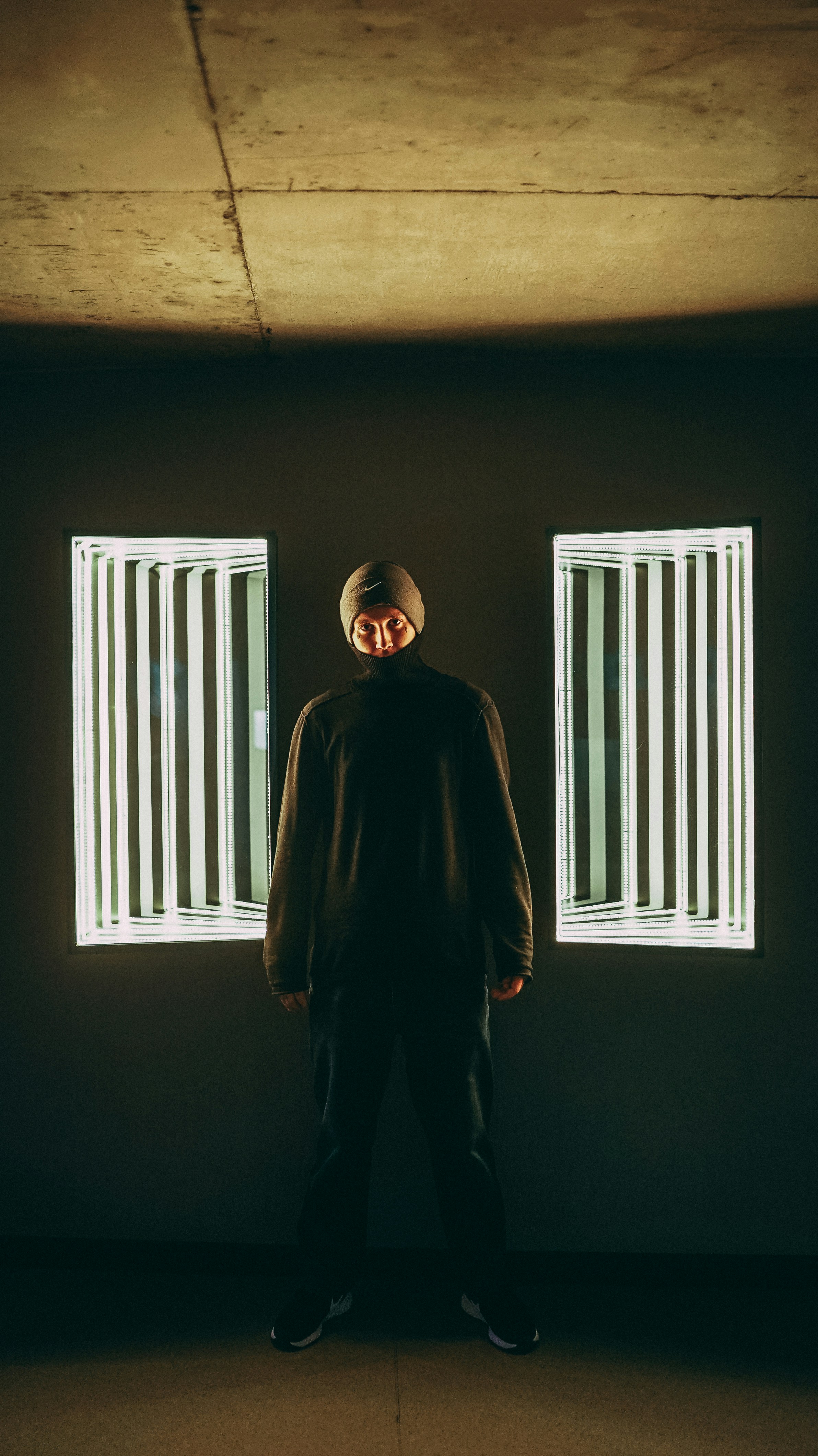 하얀 창문 블라인드 근처에 서 있는 검은 재킷을 입은 남자