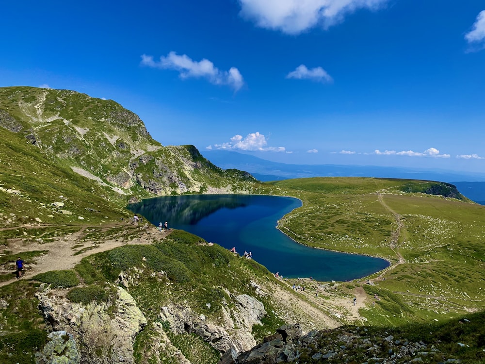 green and gray mountain beside blue lake under blue sky during daytime