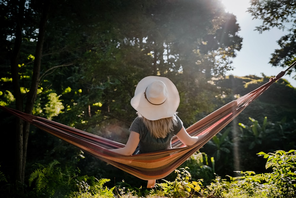 woman in white sun hat sitting on brown wooden bench