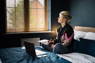 woman in black and pink floral long sleeve shirt sitting on bed