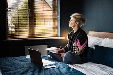 woman in black and pink floral long sleeve shirt sitting on bed