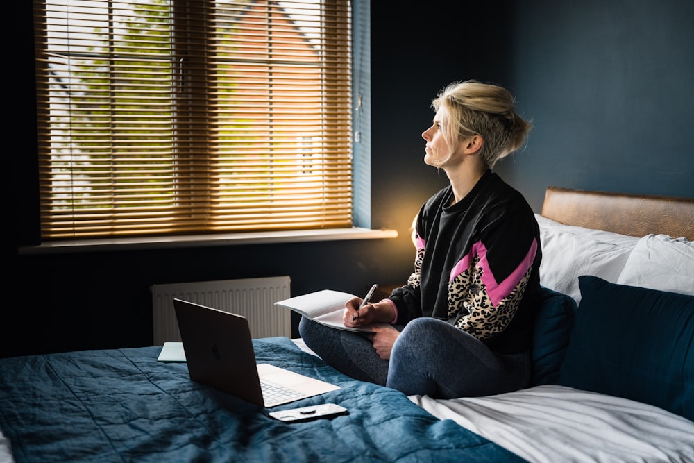 woman in black and pink floral long sleeve shirt sitting on bed