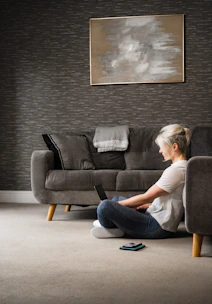 woman in white t-shirt and blue denim jeans sitting on black sofa