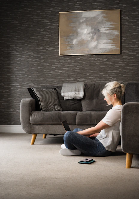 woman in white t-shirt and blue denim jeans sitting on black sofa