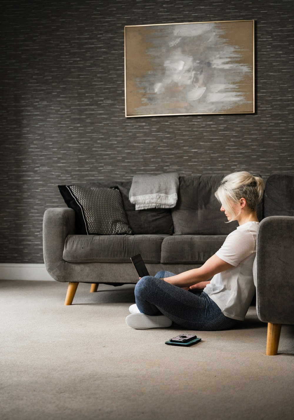 woman in white t-shirt and blue denim jeans sitting on black sofa
