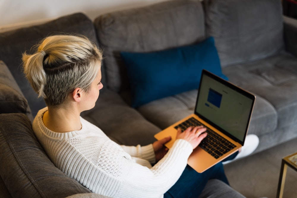 woman in white knit sweater using macbook air