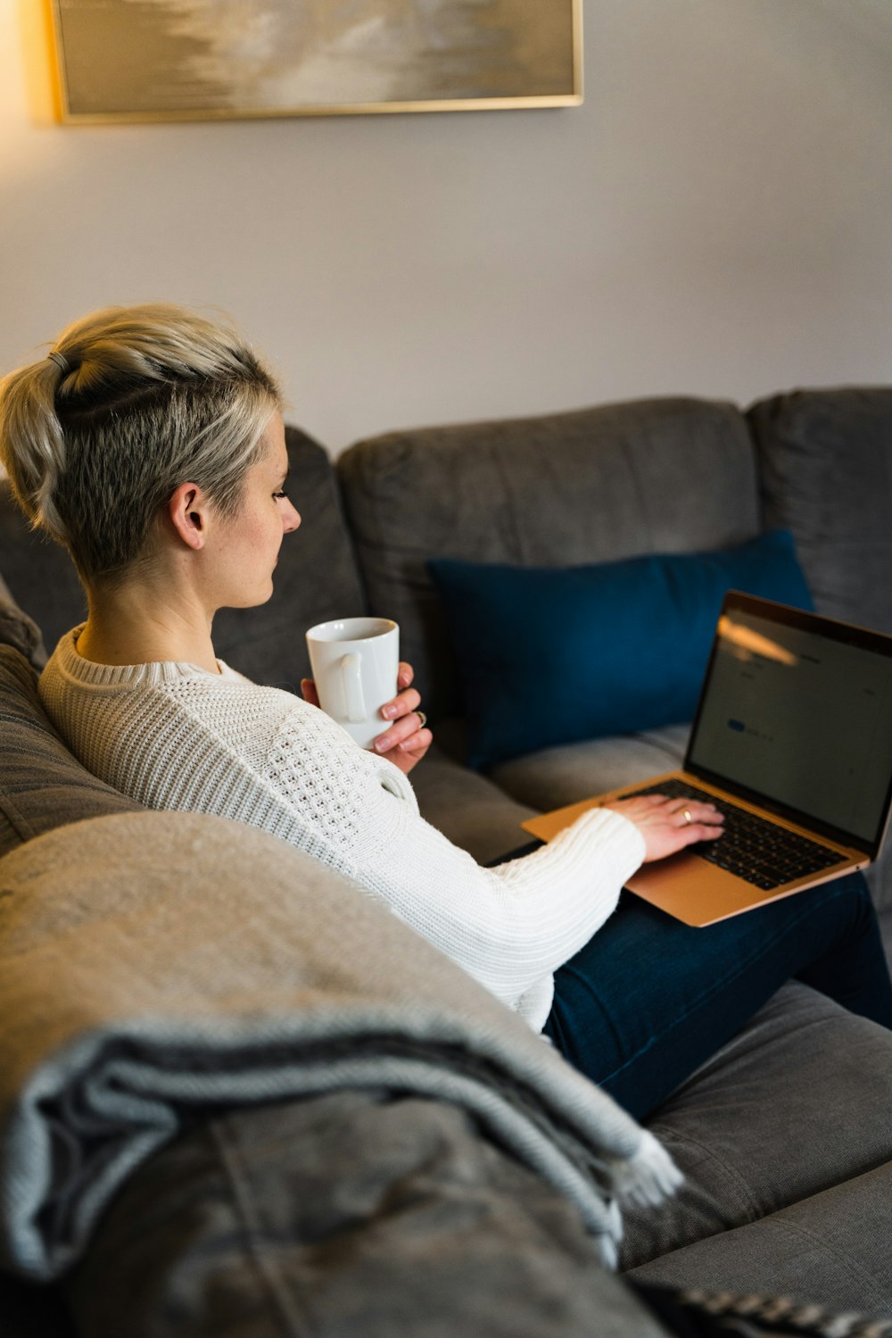 woman in white sweater using macbook air