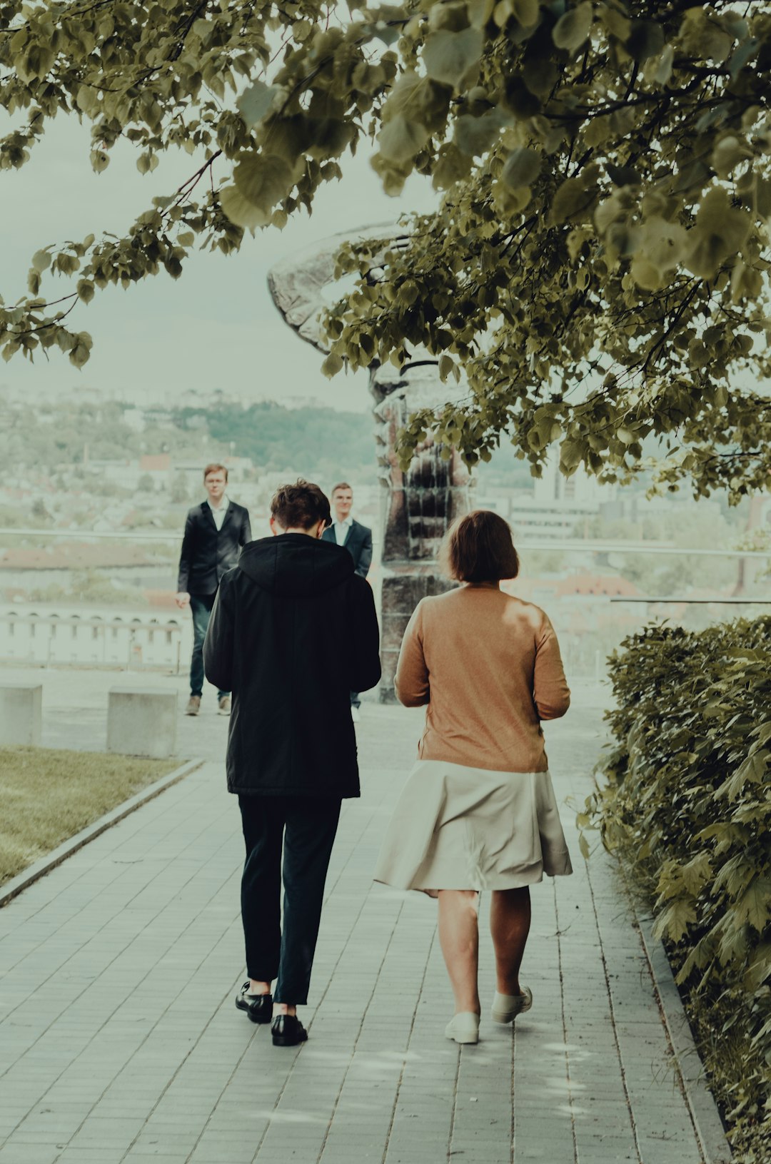 man in black suit standing beside woman in orange dress