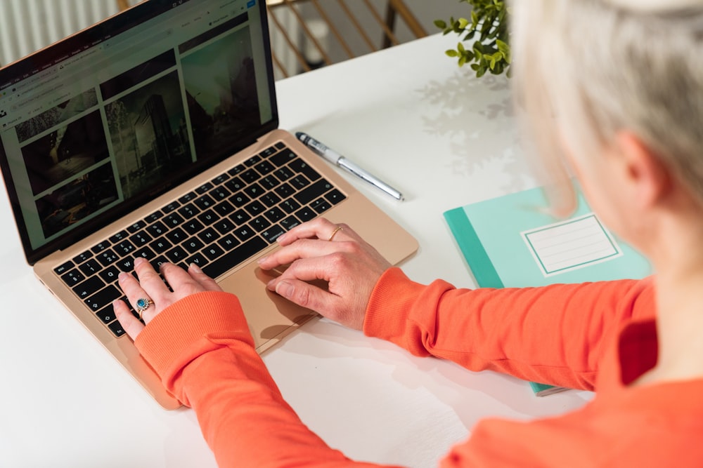 person in orange long sleeve shirt using macbook pro