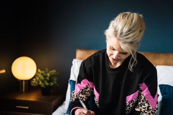 A serene boho chic woman in taupe and soft pink tones, journaling peacefully in a minimalist, sunlit room.