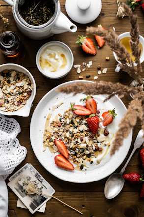A sunlit breakfast table set with fresh Greek yogurt, honey, seasonal fruits, and a cup of coffee, overlooking the old town of Nafplio.