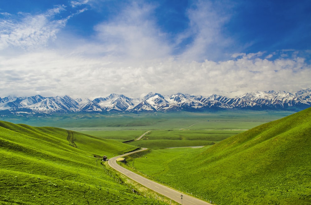 green grass field near mountain under blue sky during daytime