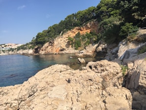 Rocky coastline with clear blue water and lush green hills