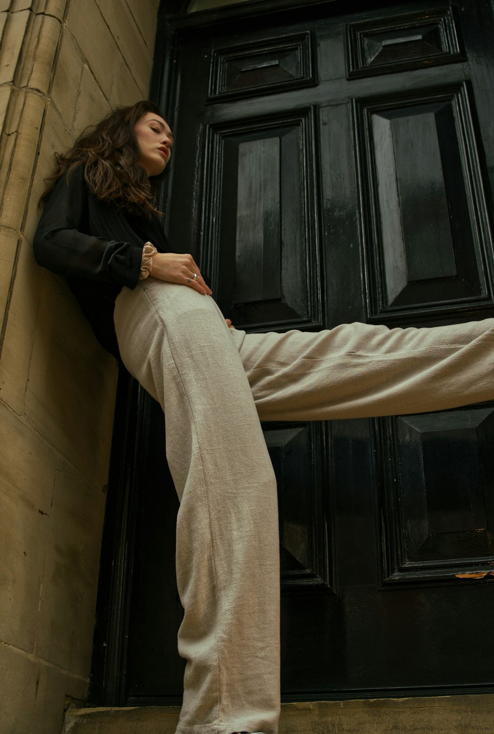 woman in black jacket and gray pants lying on brown couch