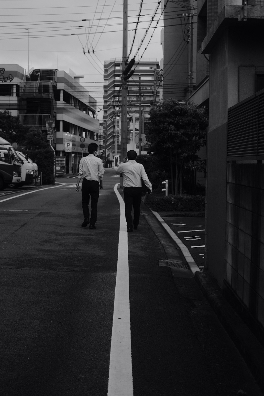 man in white dress shirt and black pants walking on pedestrian lane in grayscale photography