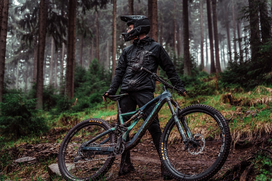 man in black jacket and black helmet riding blue mountain bike