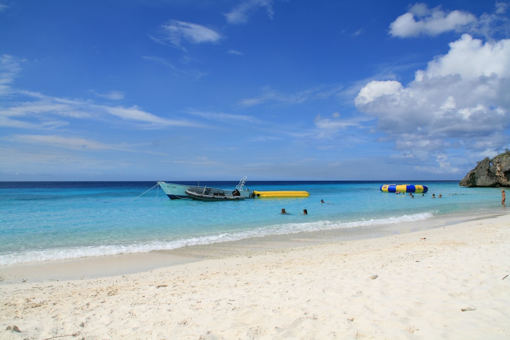 white and blue boat on sea shore during daytime