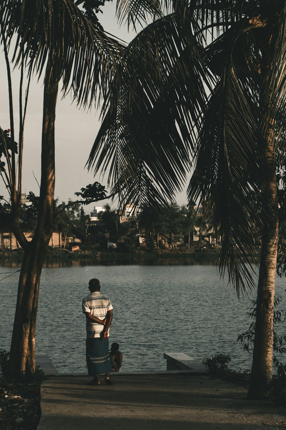 man in black shirt sitting on brown wooden dock during daytime