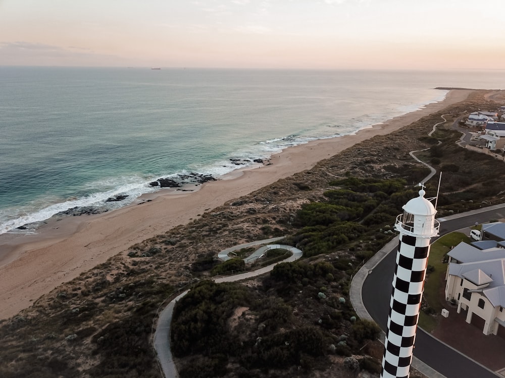 aerial view of white lighthouse near body of water during daytime