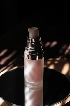 Close-up of a frosted glass nail gel bottle with gradient spraying under soft light