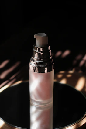 A delicate glass bottle spraying a fine mist over glowing, hydrated skin in soft natural light