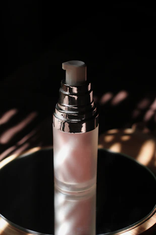 A futuristic skincare bottle with metallic textures reflecting soft light in a dark setting.