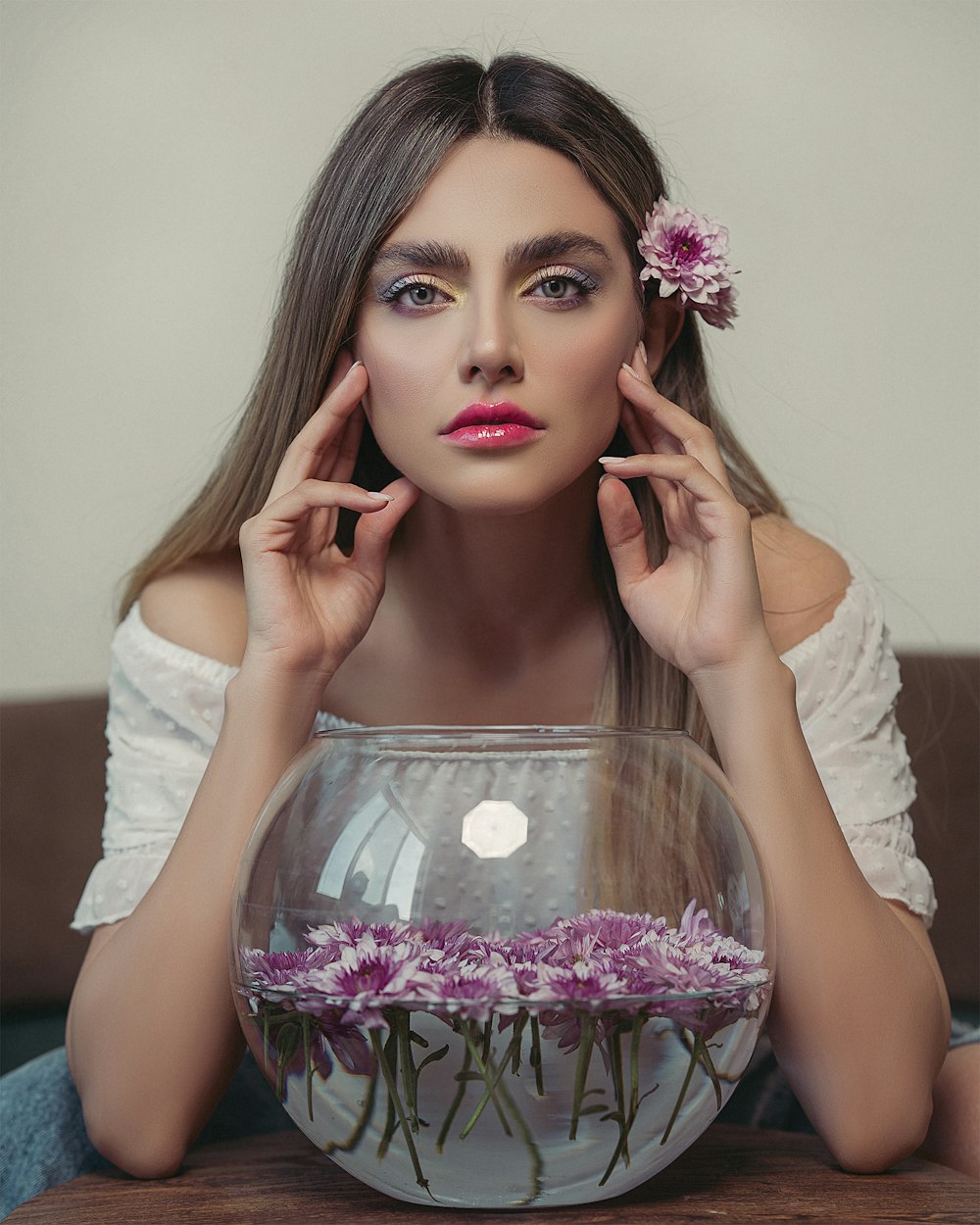 woman in white long sleeve shirt holding clear glass bowl with pink flowers