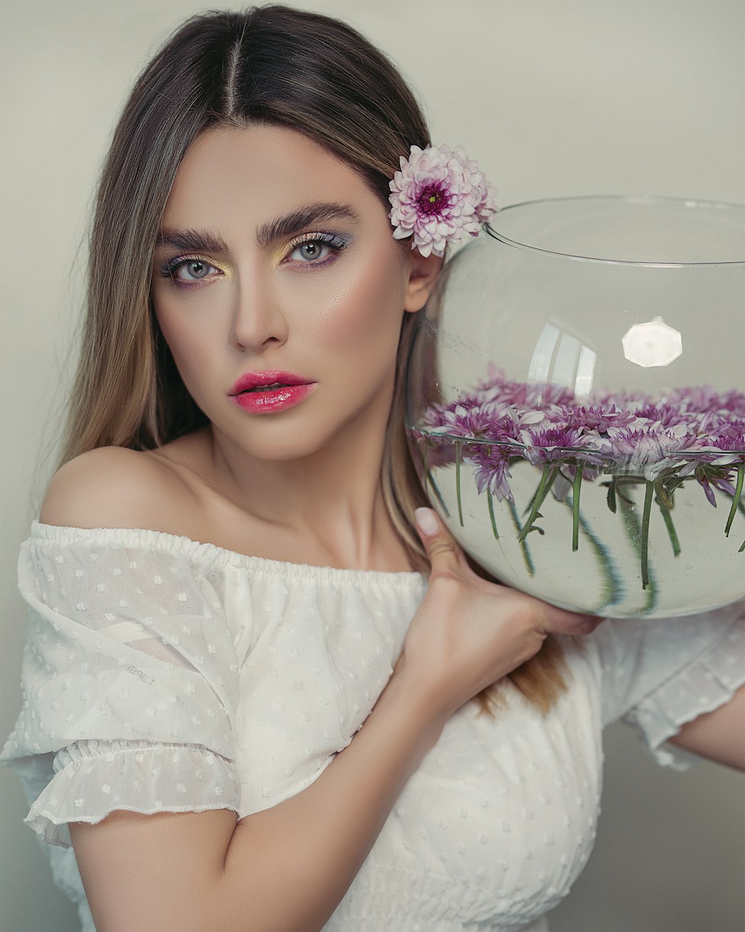 woman in white floral dress holding clear glass bowl with pink flowers