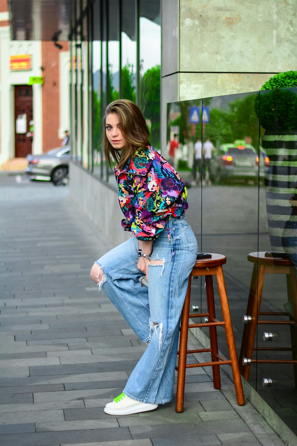 woman in blue denim jeans sitting on brown wooden seat