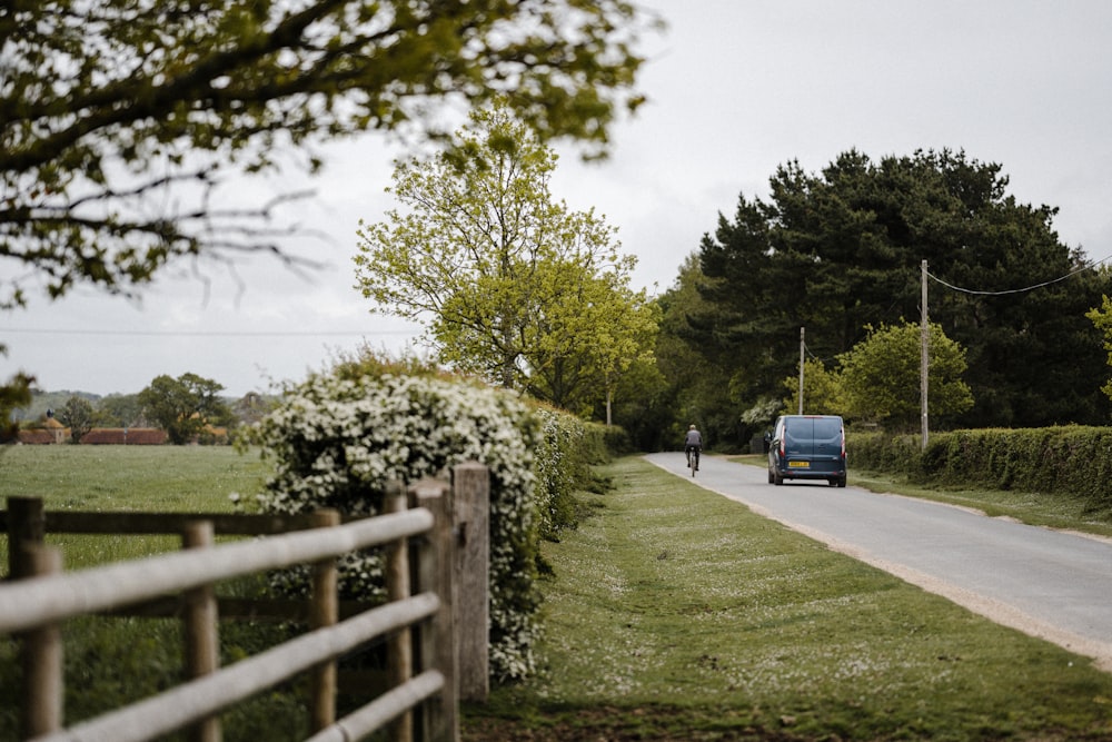 blue car on road near green grass field during daytime