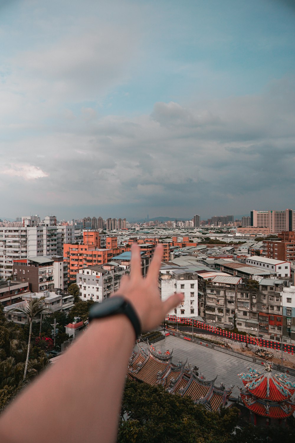 person wearing black watch and black strap watch pointing at city buildings during daytime