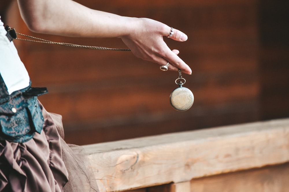 person holding silver round pendant necklace